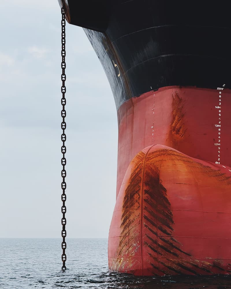 Anchor chain running down from the red bow of a ship